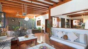 A spacious living area with wooden beams, a stone wall, and a white sofa with striped cushions. - Boutique Boho Glam Villa With Private Pool (Yaiza)