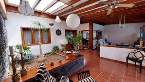 A spacious living area with a wooden ceiling, a stone fireplace, and a seating area with a zebra-striped cushion. - Boutique Boho Glam Villa With Private Pool (Yaiza)