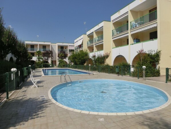 Relax by the hotel's two pools, surrounded by lush greenery and a paved walkway.