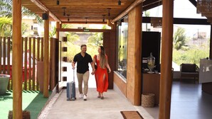 A covered walkway with a wooden ceiling, a tiled floor, and a view of greenery outside. - Uri Pousada (Maragogi)