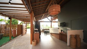 A spacious indoor area with a wooden ceiling, a reception desk, and a seating area. - Uri Pousada (Maragogi)