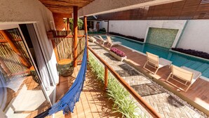 A poolside area with lounge chairs, a hammock, and a wooden deck. - Uri Pousada (Maragogi)
