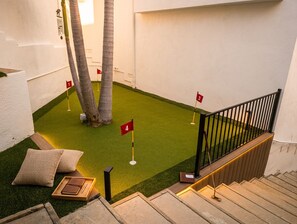 Et lille indendørs putting green med nummererede flag, en trappe og et gelænder.