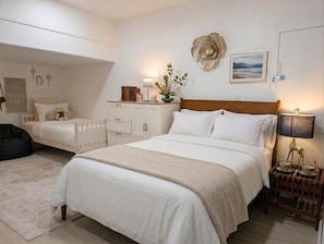 A bedroom with a large bed, a smaller bed, a nightstand with a lamp, a wall decoration, and a bedside table with a lamp. - Malibu retreat, Panoramic views, Hot tub, Golf (Malibu)