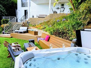 A hot tub with lounge chairs, a wooden deck, and a stone wall. - Malibu retreat, Panoramic views, Hot tub, Golf (Malibu)