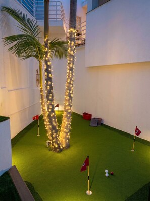 A miniature golf course with artificial palm trees and flags.