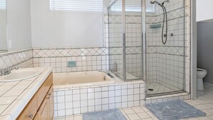 Et badeværelse med brusekabine med glasvægge, badekar og toilet.