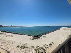 A beach with a clear sky, a sandy shore, and a rocky breakwater.