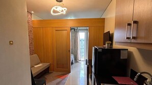 A modern kitchen with a sink, cabinets, and a dining area with a sofa and rug. - Apartment hotel in front of biggest mall of asia with resort type amenity pool.  (Pasay)