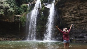 Una cascada con agua cayendo en cascada sobre un risco rocoso hacia un estanque.