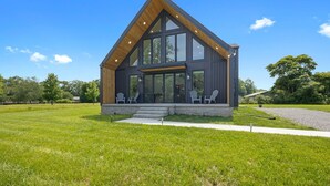 Una casa moderna con un porche grande, ventanas amplias y techo inclinado.