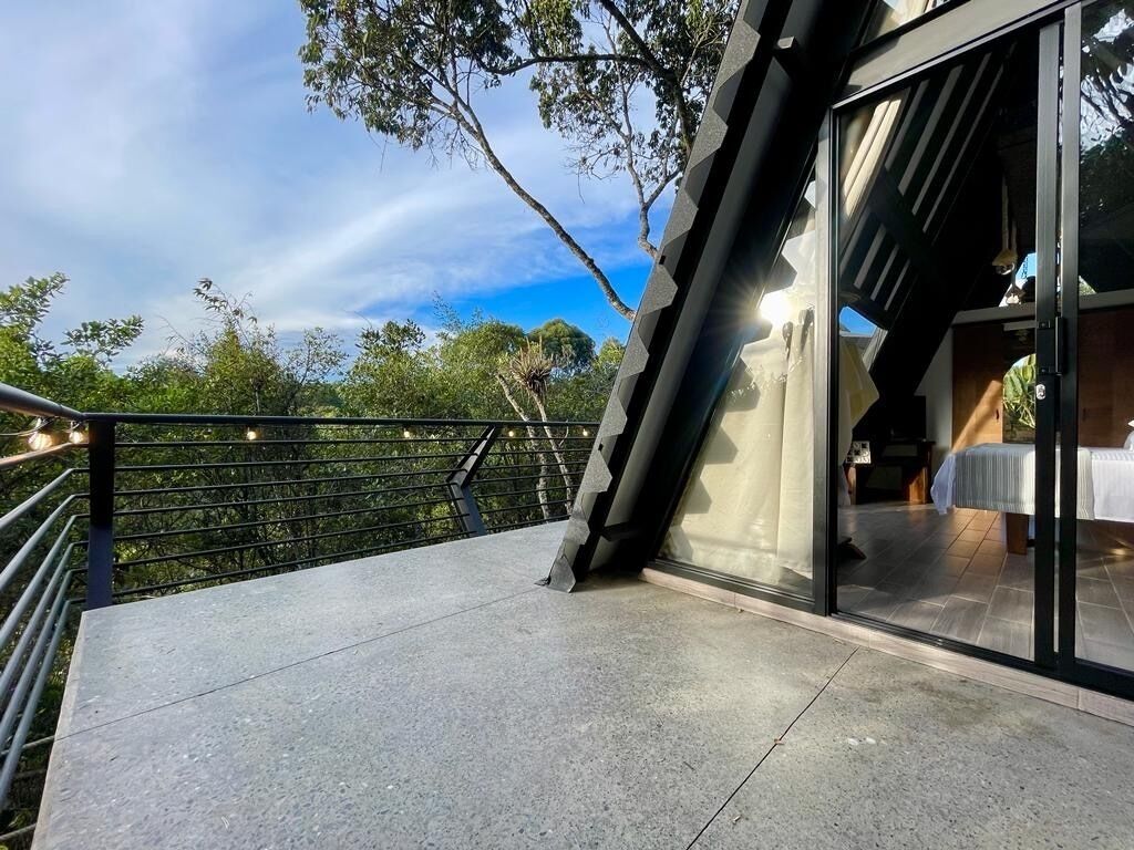 A modern building with a glass entrance and a balcony overlooking a lush garden.