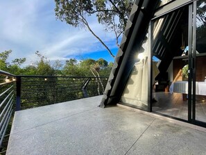 A modern building with a glass entrance and a balcony overlooking a lush garden. - Ecoluxury glamping (El Carmen de Viboral)