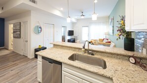 A modern kitchen with granite countertops, a stainless steel sink, and white cabinetry.