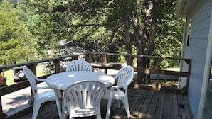 A wooden deck with a round table and four white chairs.