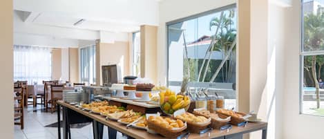 A buffet setup with various food items and a dining area with chairs and tables.