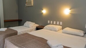Une chambre d’hôtel avec deux lits simples, une table de chevet, un radiateur fixé au mur et deux lampes fixées au mur.