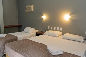 A hotel room with two single beds, a bedside table, a wall-mounted heater, and two wall-mounted light fixtures. - Hanna Praia Hotel (Florianópolis)