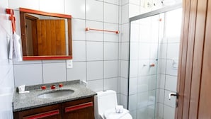 Une salle de bain avec un lavabo en granit, des meubles en bois, des toilettes blanches, une cabine de douche en verre et un miroir avec un cadre en bois.