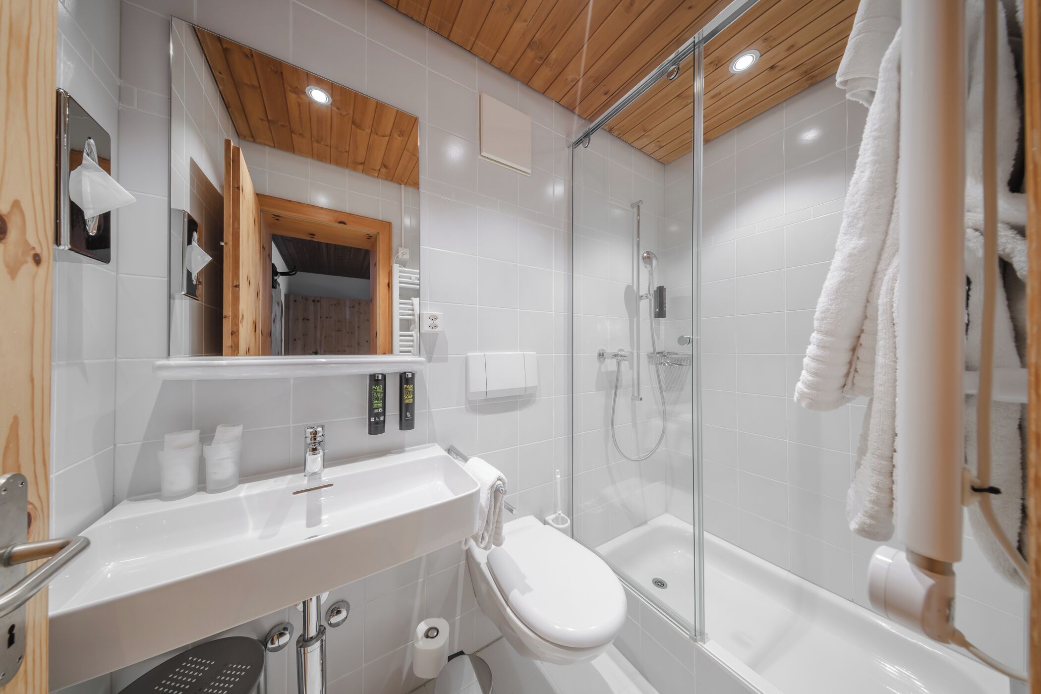 A modern bathroom with a glass-enclosed shower, a white sink, and a toilet.