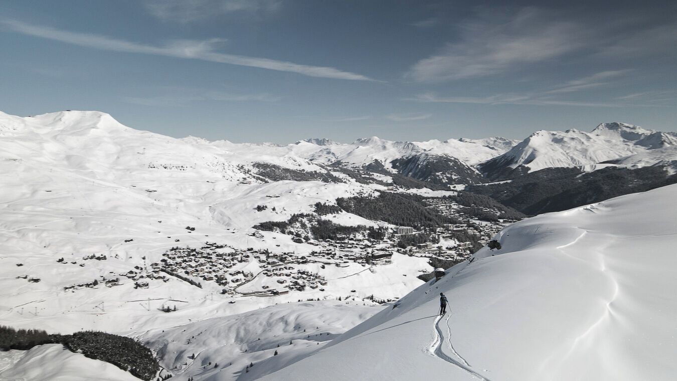 A snow-covered mountain landscape with a ski resort in the valley.