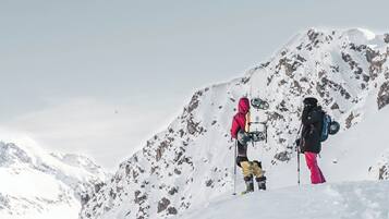 Deux personnes se tiennent debout sur une montagne enneigée, sous un ciel dégagé.