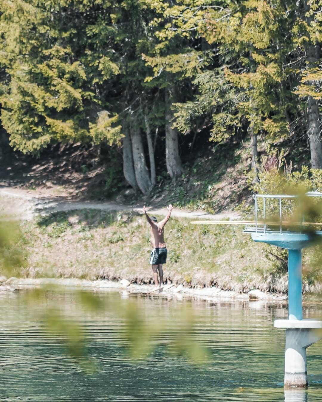 A person jumping into a body of water from a concrete platform.
