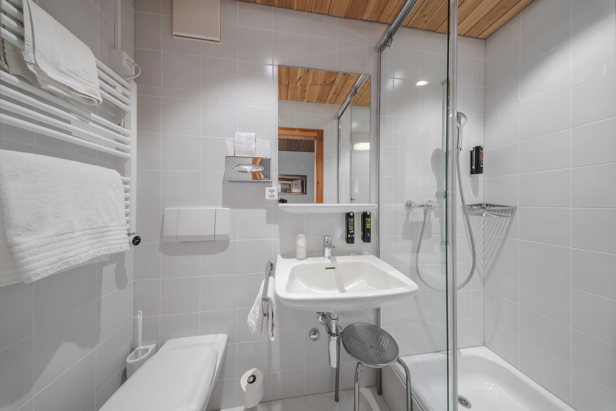 Un baño moderno con lavamanos, inodoro y ducha blancos.
