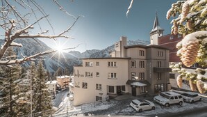 Un hotel de varios pisos, una aguja de iglesia y un aparcamiento con coches.