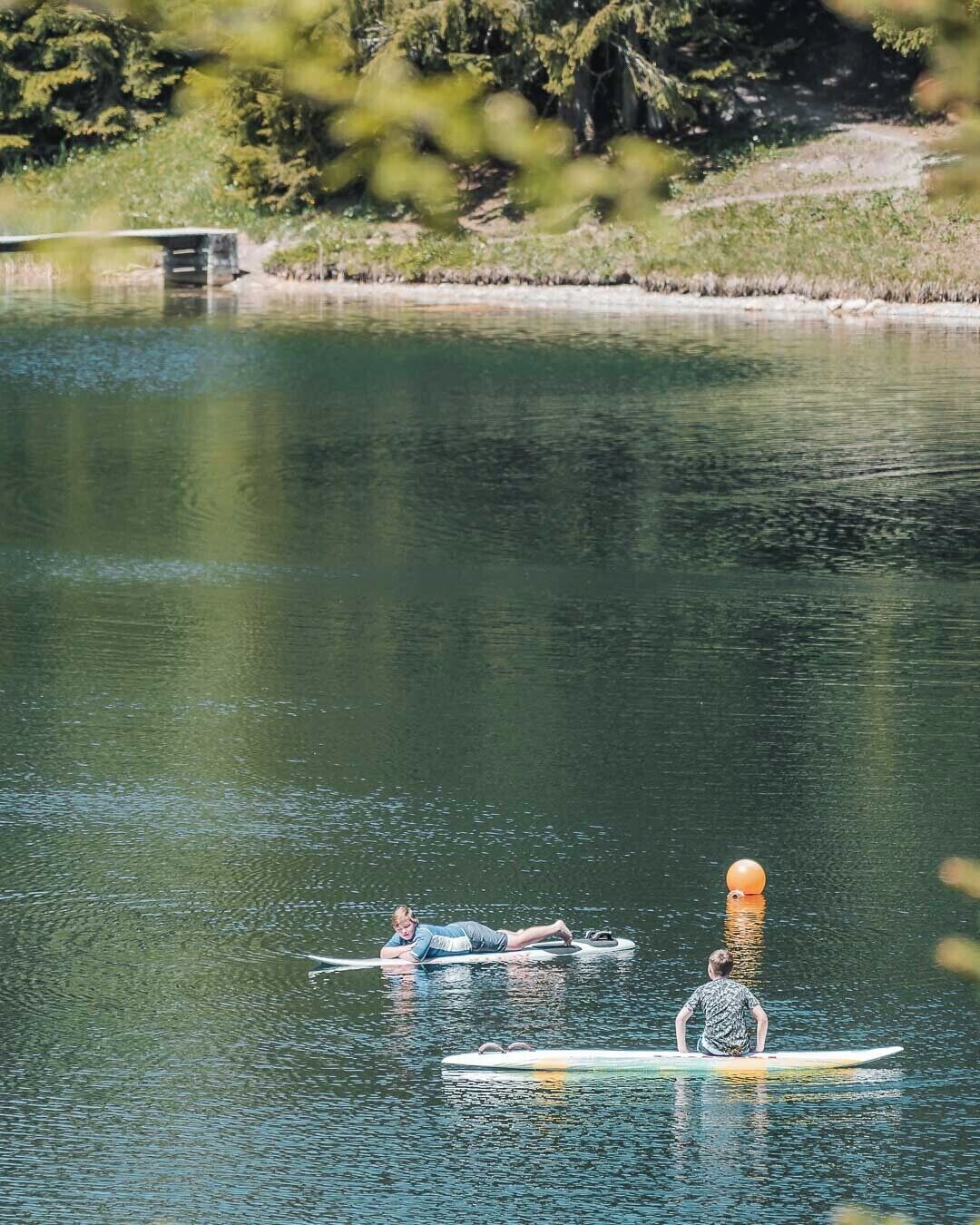 A calm lake with two people paddling kayaks.