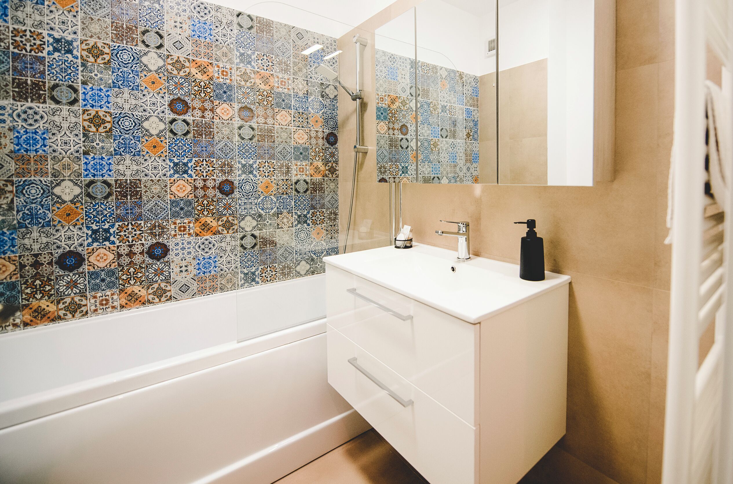 Un baño con pared de azulejos, un lavabo blanco, un espejo y una ducha.