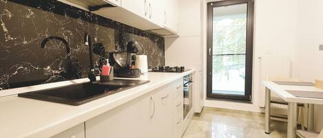 A modern kitchen with a black marble backsplash, white cabinets, a stainless steel sink, and a dining area with a table and chairs.