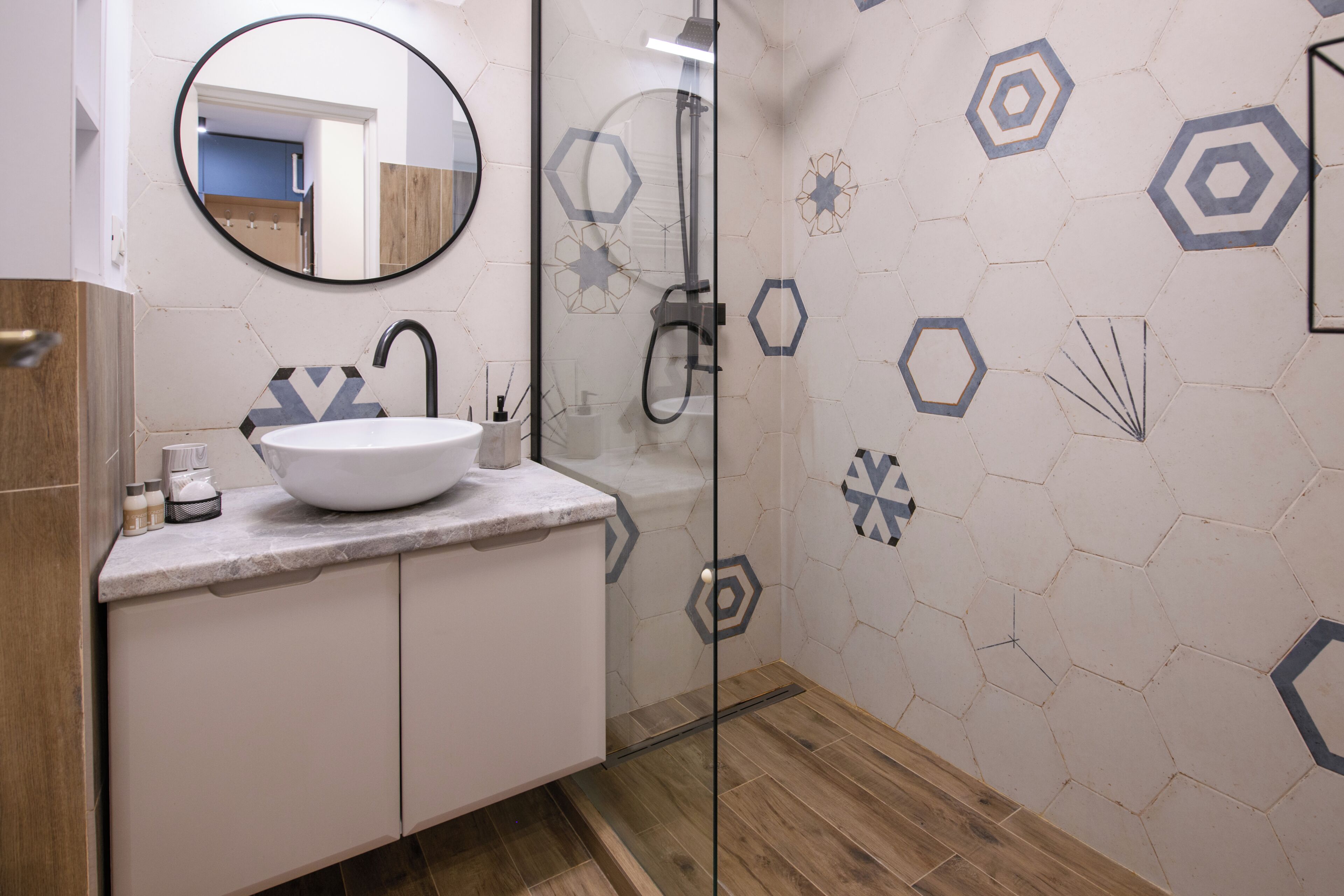 Un baño moderno con un lavamanos, espejo y ducha blancos.