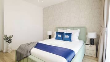 A modern hotel room with a bed, nightstands, a lamp, and a plant.