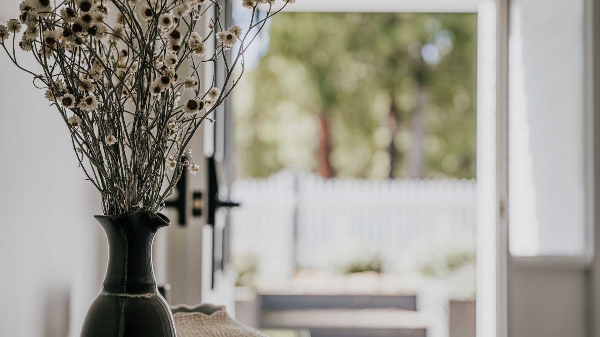 A vase with dried flowers on a windowsill.