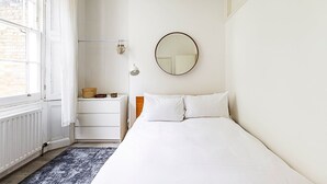 Un dormitorio con cama, cómoda, espejo y ventana.