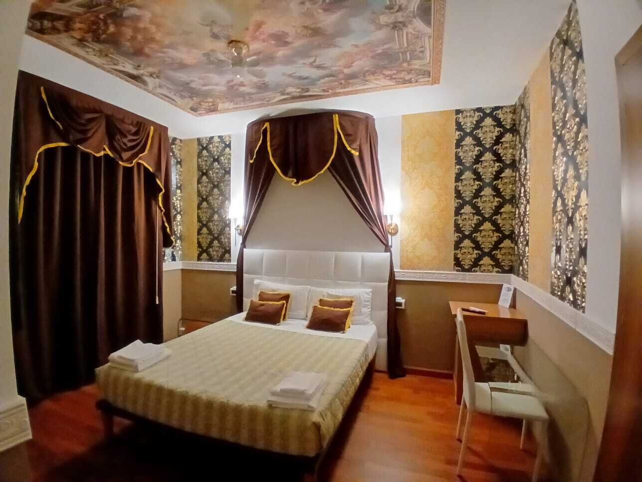 A hotel room with a large bed, a desk, and a chair.