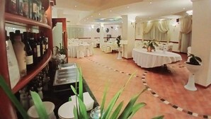 Ein geräumiger Hotel-Speisesaal mit mehreren runden Tischen, einer Weinauslage und einer zentralen Blumenkomposition.