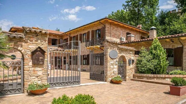 Ein Steinhaus mit einem verschlossenen Eingang, einem Balkon und Topfpflanzen.
