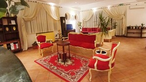Ein Wohnzimmer mit einem roten Sofa, weißen Sesseln, einem Couchtisch und einem Teppich mit rotem und weißem Muster.
