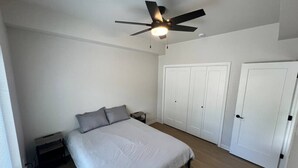 Un dormitorio con cama, ventilador de techo y armario.