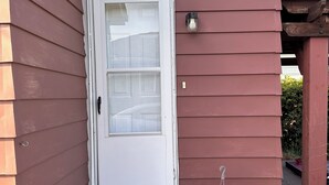 A house with a white front door, a small porch with steps, and a welcome mat. - Modern Tiny Home Escape (Garfield Heights)