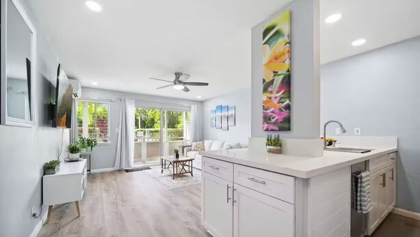 A modern kitchen with a large island, white cabinetry, and a view to a patio area. - NEW! FULLY UPDATED ground floor condo with AC! (Kapaʻa)