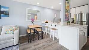 A modern kitchen with a white island, bar stools, and a stainless steel refrigerator. - NEW! FULLY UPDATED ground floor condo with AC! (Kapaʻa)