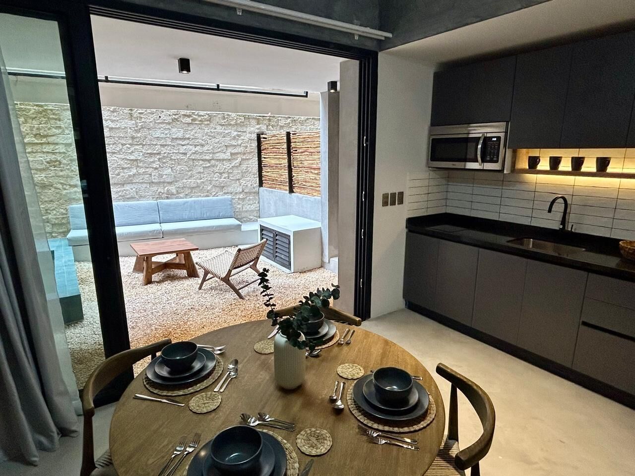 A modern kitchen with dark cabinets, a microwave, and a dining area with a table set for four.