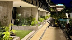 Un edificio moderno con facciata in vetro, pilastri in cemento e aree esterne con piante.