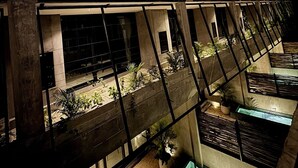 Un edificio a più piani con un design architettonico moderno, caratterizzato da balconi con piante e una terrazza sul tetto.