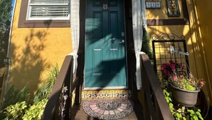 Edifici groc amb una porta verda, una finestra petita i un senyal amb el número '319'.