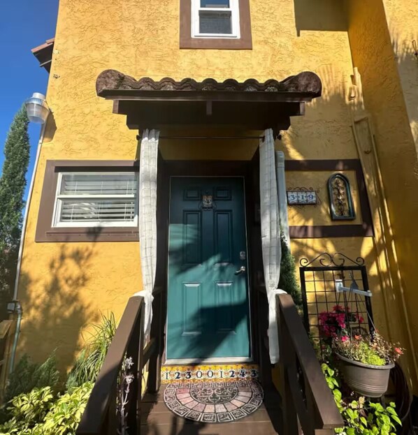 Um edifício amarelo com porta verde, uma pequena janela e uma placa com o número 319.