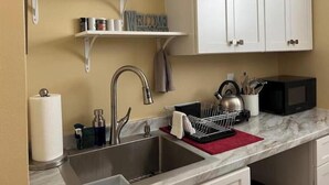 A kitchen with white cabinets, a stainless steel sink, and a microwave. - Unit Number 4 (New Smyrna Beach)